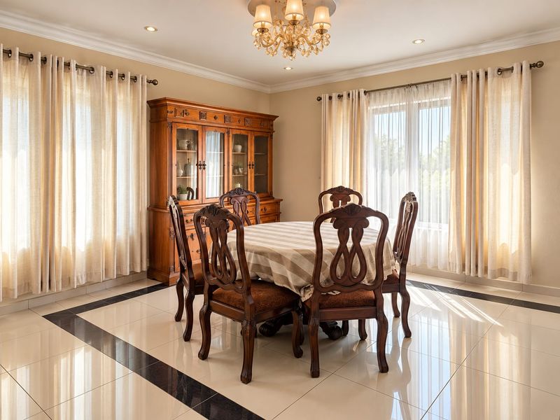 A bright and elegant dining room featuring polished porcelain flooring with a decorative border, crown molding, and a classic chandelier.