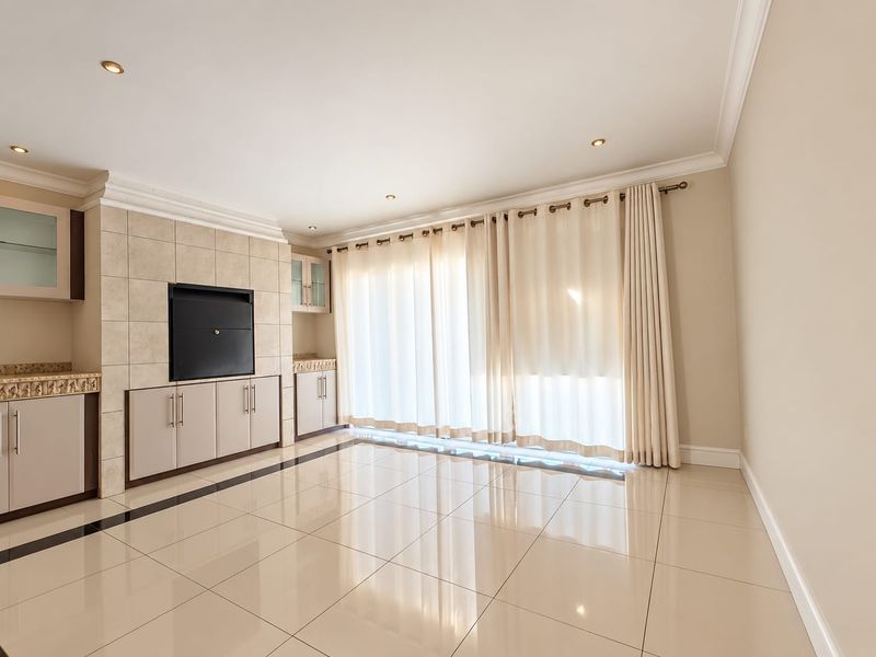 Spacious living area featuring polished tiled floors, built-in cabinetry with a fireplace, and large sliding doors leading to the exterior.