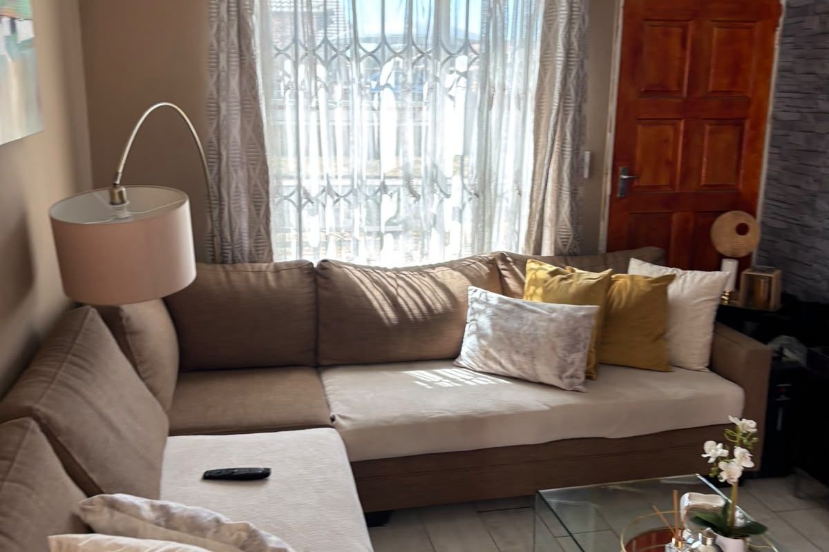 A comfortable living room featuring tiled flooring, recessed downlighting, and a stone-cladding feature wall, providing a warm and inviting atmosphere.