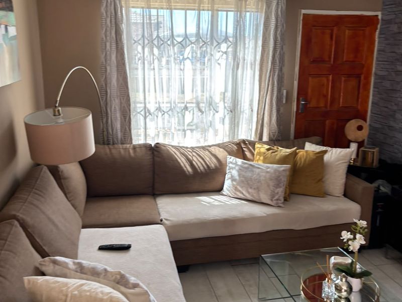 A comfortable living room featuring tiled flooring, recessed downlighting, and a stone-cladding feature wall, providing a warm and inviting atmosphere.