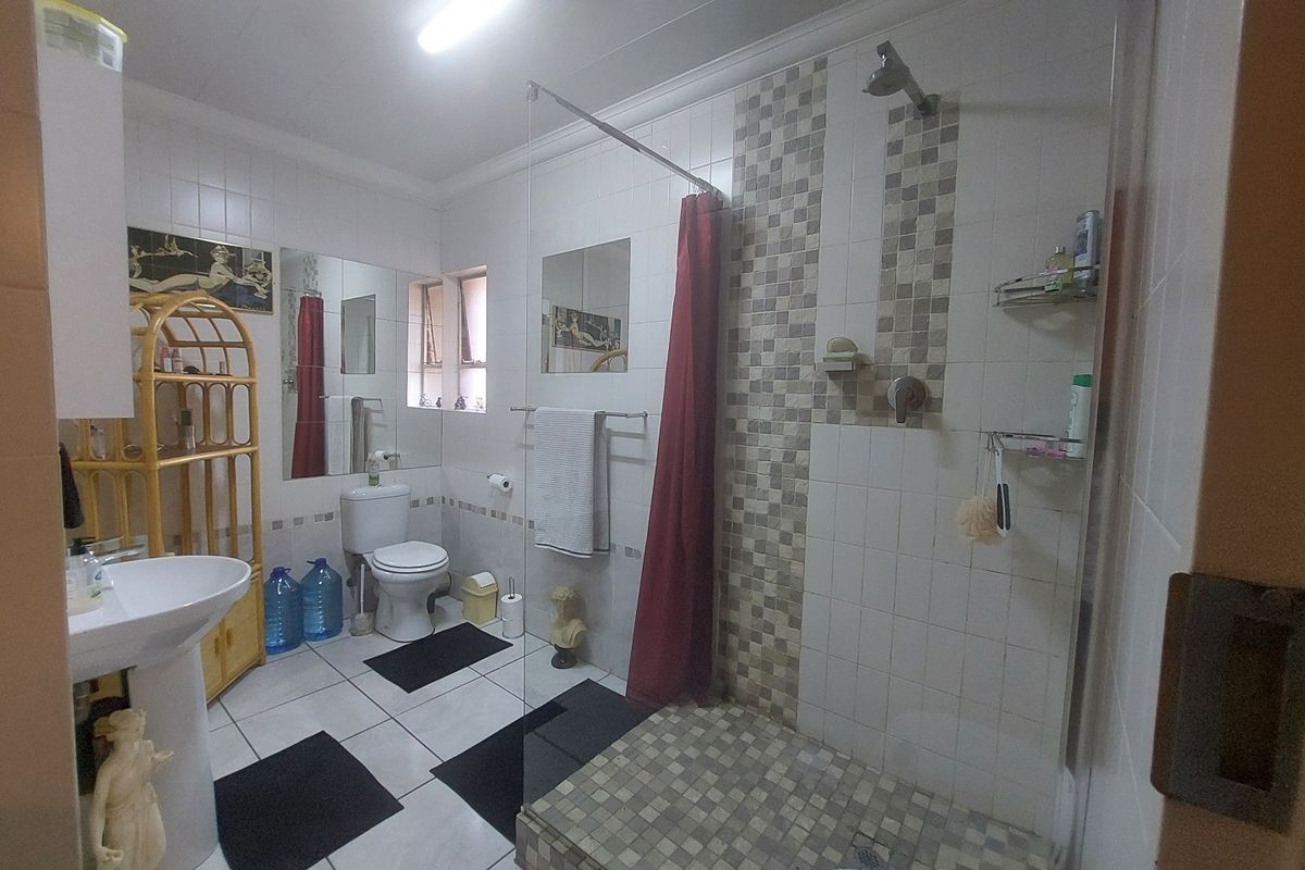 A functional bathroom featuring a pedestal basin, toilet, and a walk-in shower with tiled finishes.