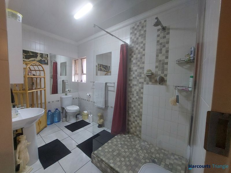 A functional bathroom featuring a pedestal basin, toilet, and a walk-in shower with tiled finishes.