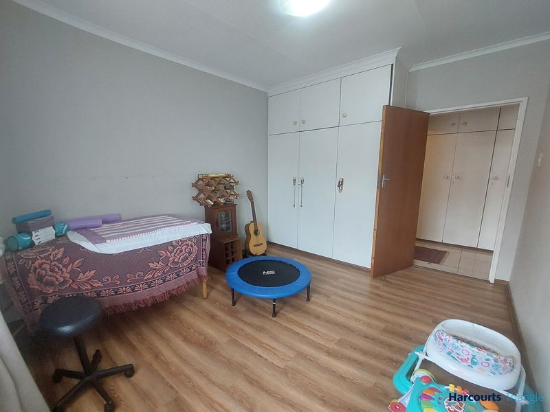 A bedroom featuring laminate flooring and extensive built-in cupboard storage, providing a functional space with neutral wall finishes.