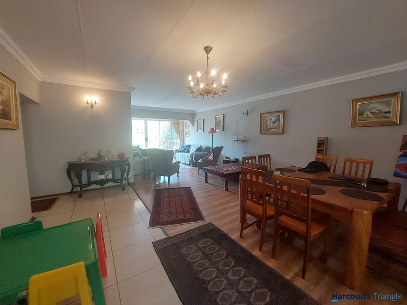 Spacious open-plan living and dining area featuring a mix of tiled and laminate flooring, coved ceilings, and a classic chandelier.