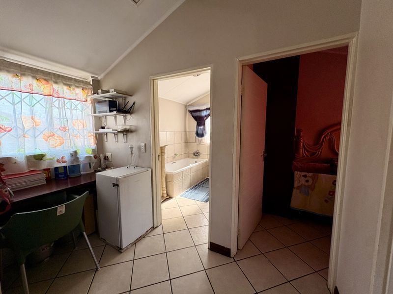A functional hallway area featuring tiled flooring and built-in shelving, providing access to an adjacent bathroom and bedroom.