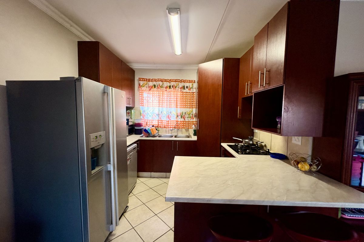 A functional kitchen featuring dark wood cabinetry, laminate countertops, a gas hob, and tiled flooring, offering a practical layout for daily meal preparation.