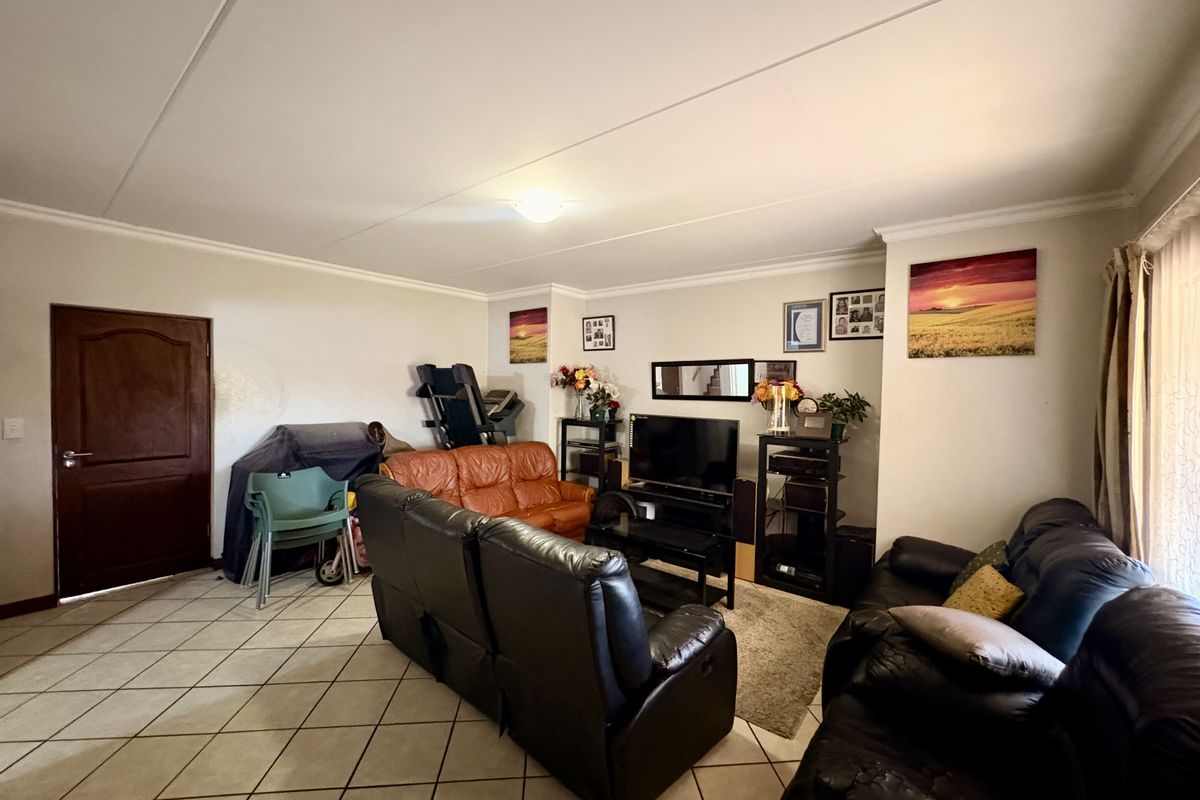 A spacious living room featuring neutral walls, tiled flooring, and coved ceiling details, providing a functional and comfortable family living area.