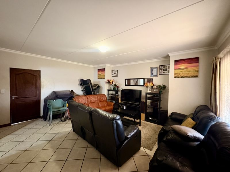 A spacious living room featuring neutral walls, tiled flooring, and coved ceiling details, providing a functional and comfortable family living area.