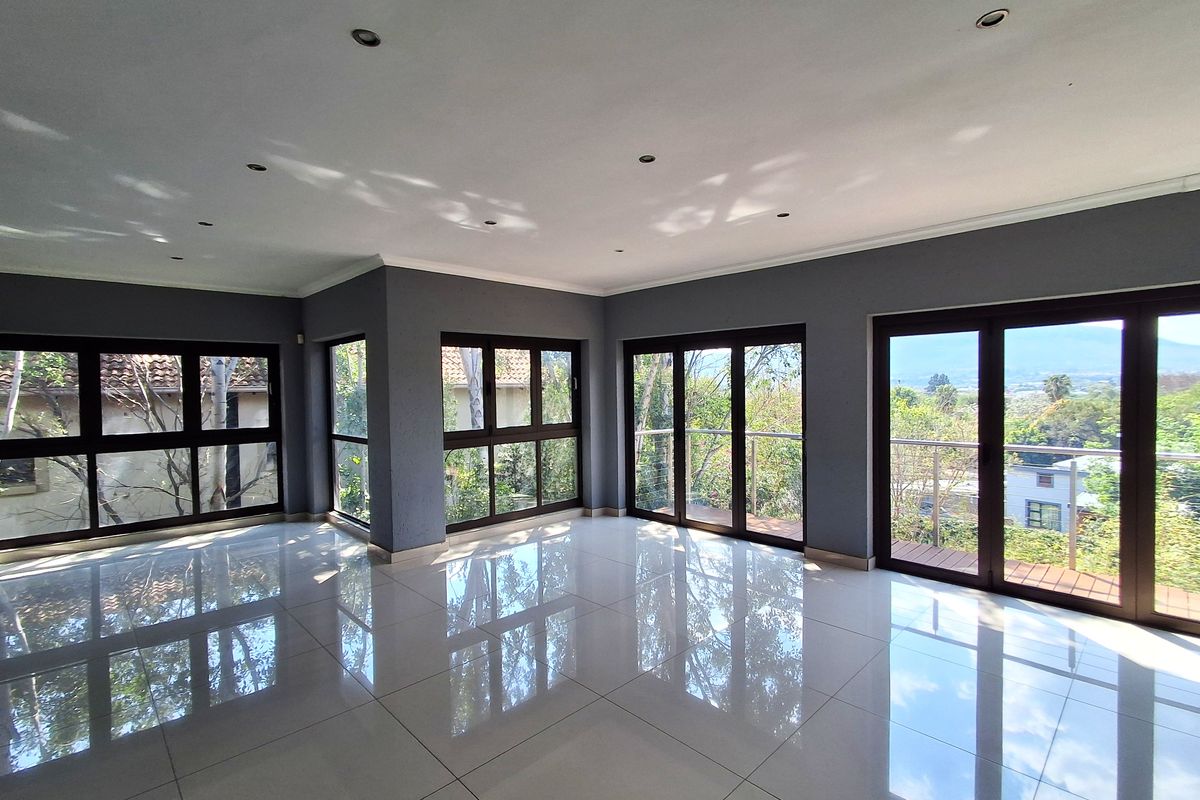 Spacious, light-filled living area featuring polished porcelain tiles, recessed lighting, and multiple glass sliding doors opening onto a balcony with scenic views.