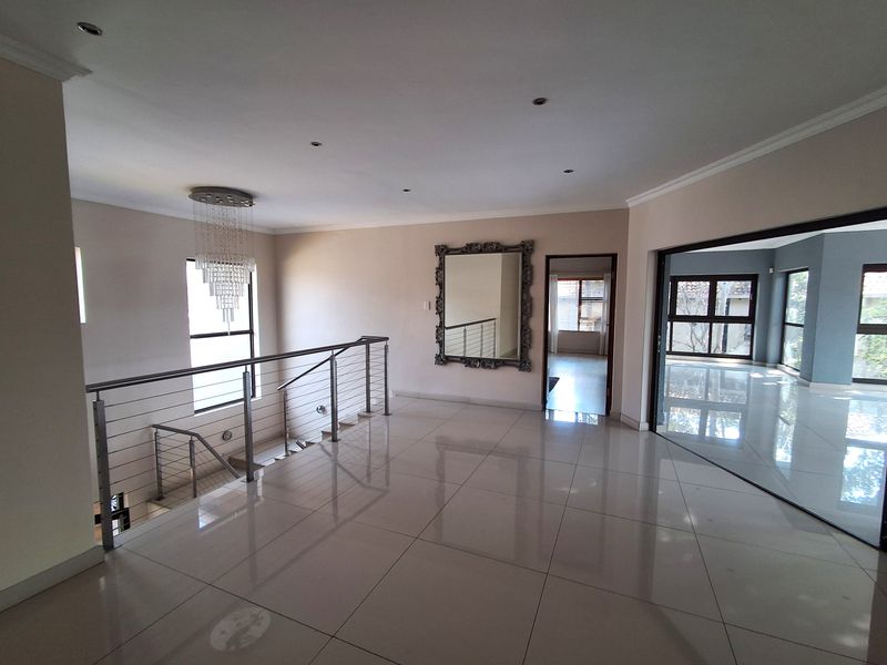 Spacious landing area featuring polished tile flooring, a modern stainless steel balustrade, and recessed lighting, providing access to adjacent living spaces.