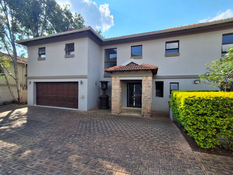 Front elevation of a two-story house featuring a paved driveway, double garage, and a stone-clad entrance porch with a tiled roof.