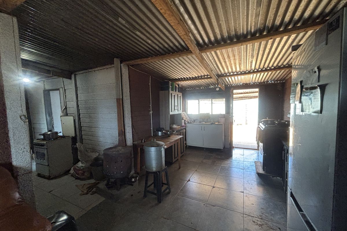 A rustic kitchen area featuring tiled floors, corrugated iron roofing, and basic cabinetry, offering significant potential for renovation and modernization.