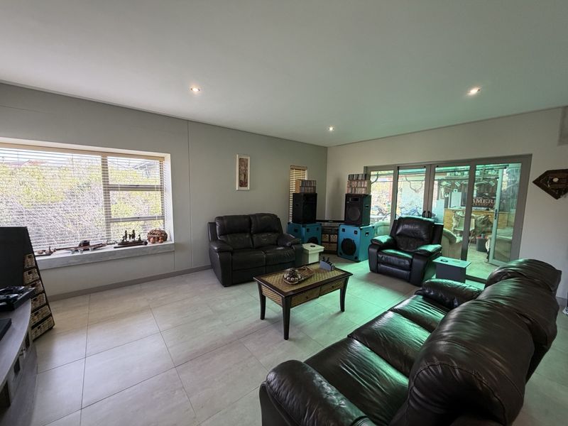 Spacious living room featuring neutral tiled flooring, recessed downlighting, and large aluminium sliding doors providing access to the outdoor area.