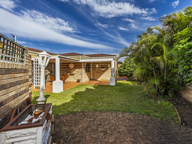 A private rear garden featuring a covered patio area, brick paving, and a built-in barbecue, perfect for outdoor entertaining.