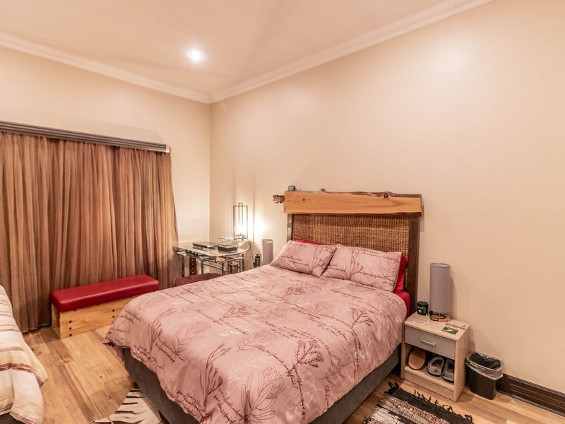 A well-proportioned bedroom featuring laminate flooring, recessed downlighting, and decorative cornice detailing.