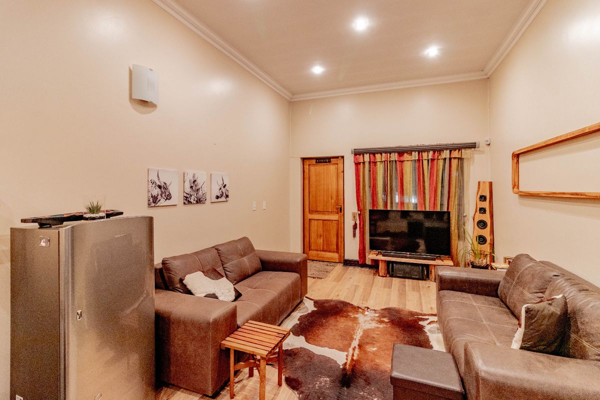 A comfortable living room featuring laminate flooring, recessed downlighting, and coved cornicing, providing a functional and inviting space.