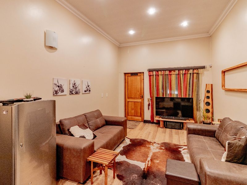 A comfortable living room featuring laminate flooring, recessed downlighting, and coved cornicing, providing a functional and inviting space.