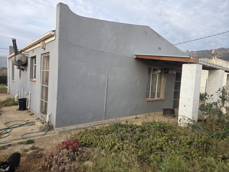 Front elevation of a single-story house featuring a covered porch area, security gates, and a textured grey exterior finish.