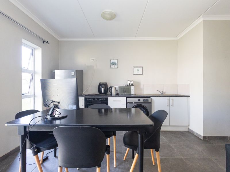Open-plan kitchen and dining area featuring tiled flooring, built-in cabinetry, and integrated appliance connections, providing a functional and versatile living space.