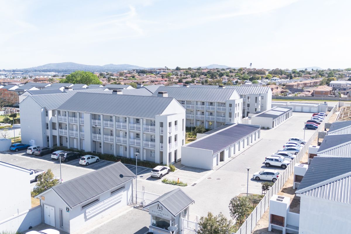 Aerial view of a modern apartment complex featuring multi-story residential blocks, paved parking, and a secure gated entrance.