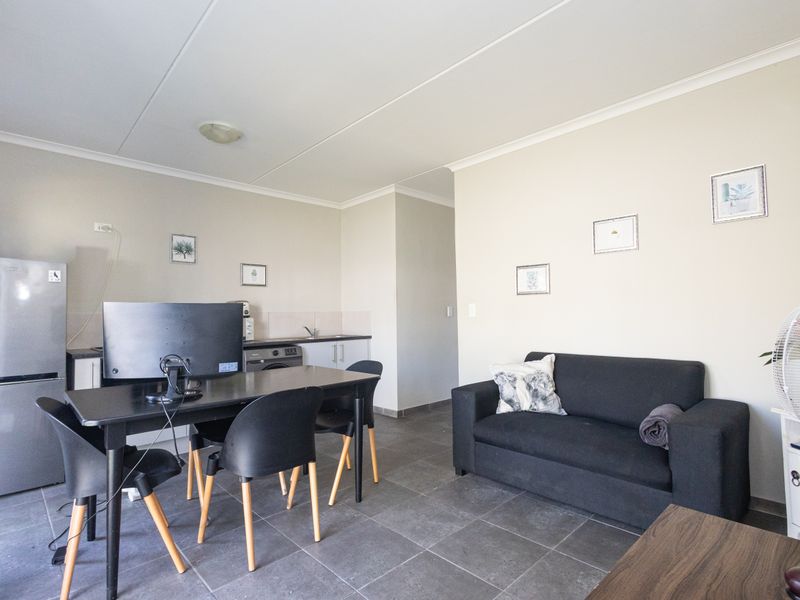 Open plan living area featuring tiled flooring and a compact kitchen corner with built-in cabinetry and sink.