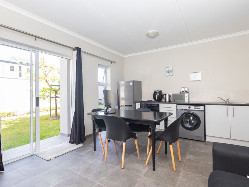 Open-plan living area featuring a functional kitchen with built-in cabinetry, integrated appliances, tiled flooring, and direct access to the outdoor patio through sliding doors.
