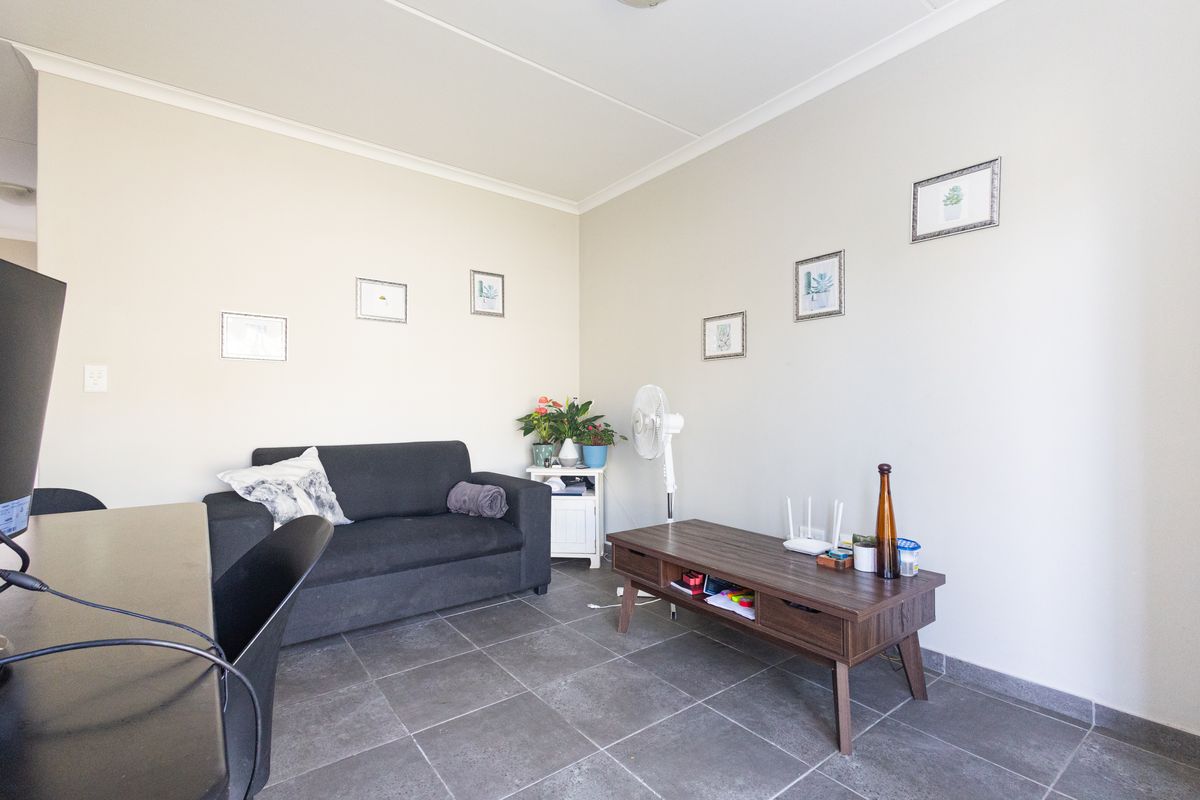 A living room area featuring neutral wall finishes and dark tiled flooring, providing a functional space for relaxation.