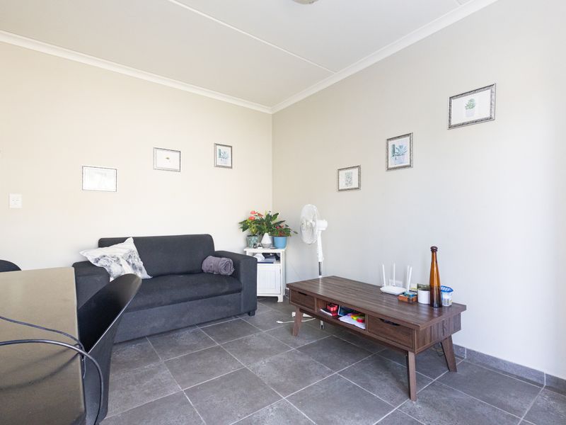 A living room area featuring neutral wall finishes and dark tiled flooring, providing a functional space for relaxation.
