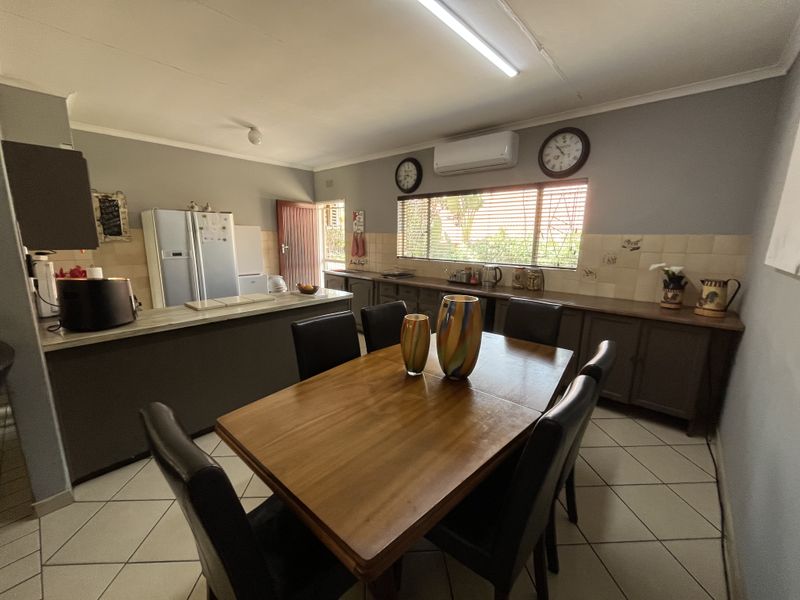 Open-plan kitchen and dining area featuring tiled flooring, ample cabinetry, a tiled backsplash, and a wall-mounted air conditioning unit.