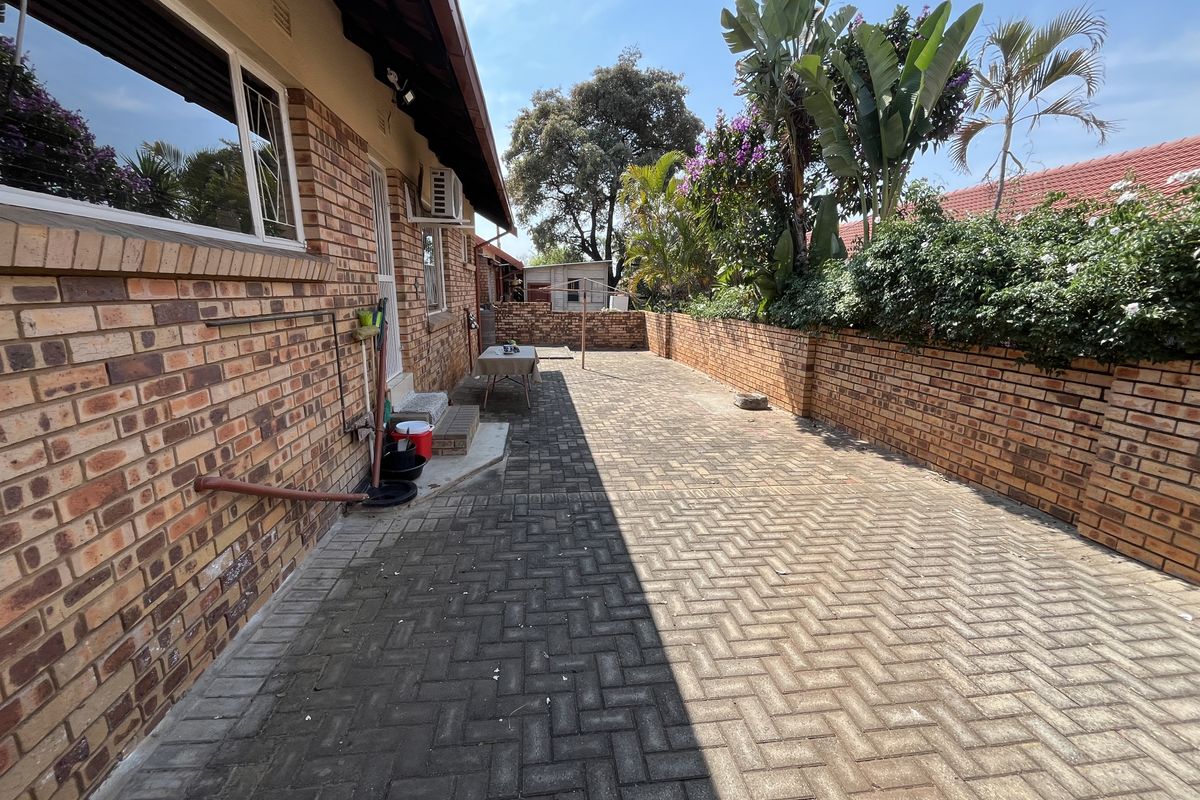 A paved rear courtyard area featuring face brick walls, a boundary wall, and an external air conditioning unit.