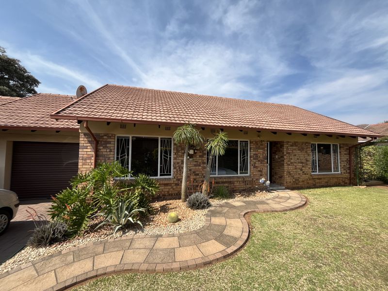 Front elevation of a brick house featuring a tiled roof, paved walkway, and integrated garage.