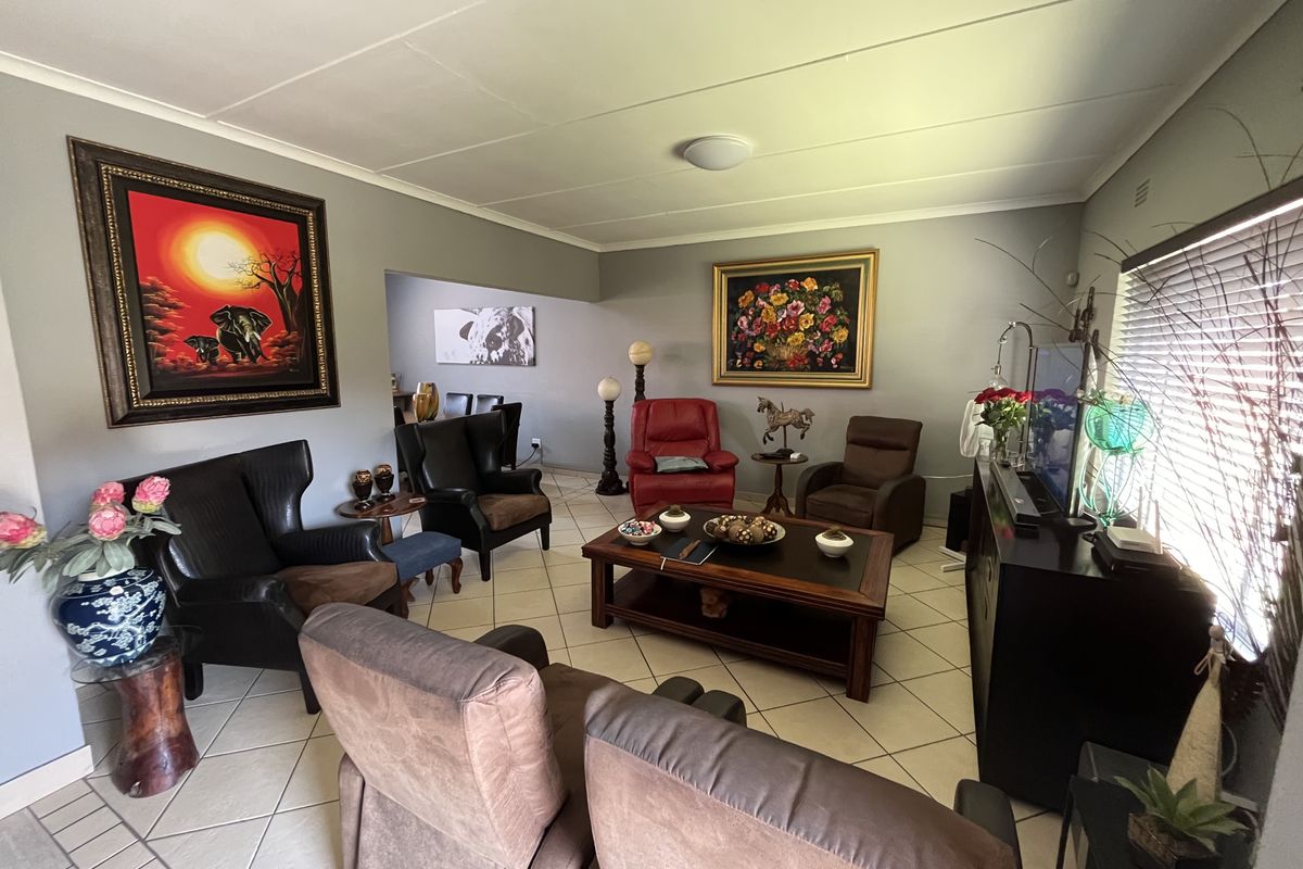 A comfortable living room featuring ceramic tile flooring and large windows with venetian blinds, offering a functional and well-maintained space.