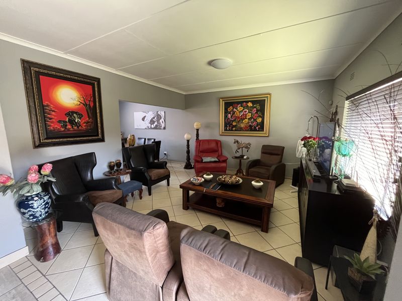 A comfortable living room featuring ceramic tile flooring and large windows with venetian blinds, offering a functional and well-maintained space.