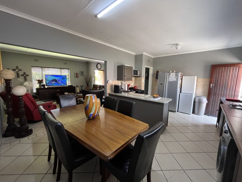 Open-plan living and dining area featuring a functional kitchen with built-in cabinetry, island, and tiled flooring throughout.