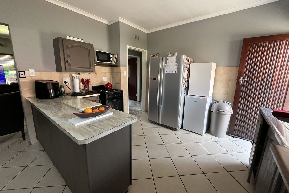 A functional kitchen featuring tiled flooring, a tiled backsplash, built-in cabinetry, and a central island with a laminate countertop.