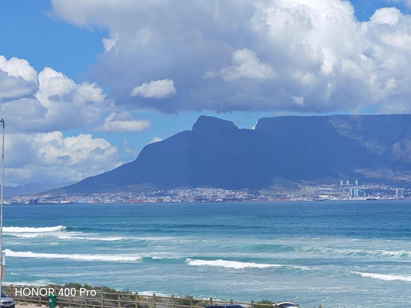 A scenic coastal view overlooking the ocean with Table Mountain in the background.