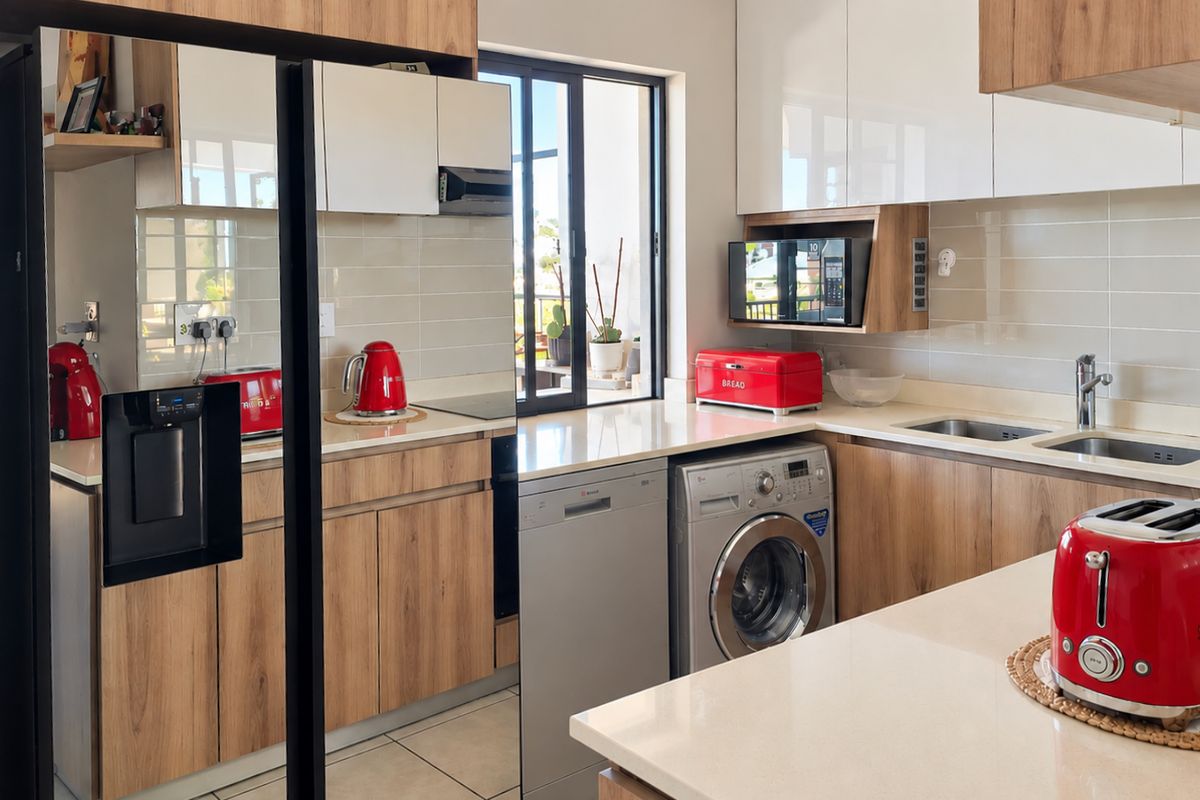 Modern kitchen featuring wood-grain and high-gloss cabinetry, stone countertops, integrated appliances, and a double basin sink with a tiled backsplash.