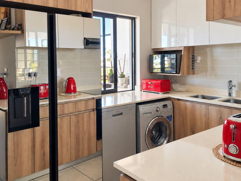 Modern kitchen featuring wood-grain and high-gloss cabinetry, stone countertops, integrated appliances, and a double basin sink with a tiled backsplash.