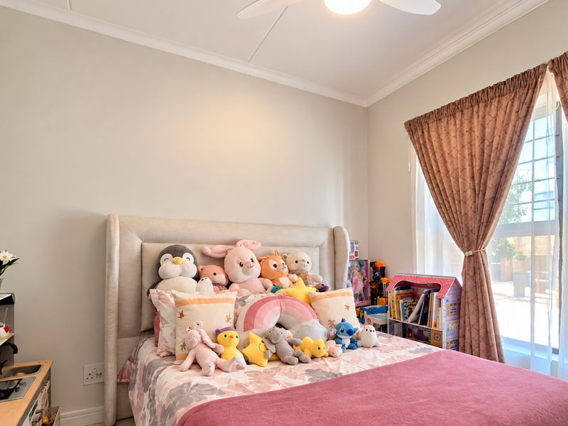 A well-maintained bedroom featuring a ceiling fan, decorative coving, and a window fitted with security bars.