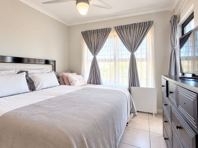 A well-maintained bedroom featuring neutral wall tones, tiled flooring, and a ceiling fan, offering a comfortable and functional living space.