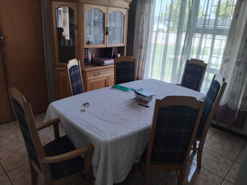 A functional dining room featuring ceramic tile flooring and a large window with natural light, providing a practical space for family meals.