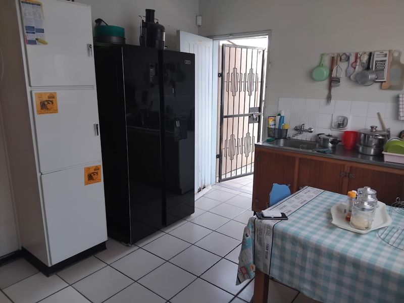 A functional kitchen area featuring tiled flooring, a stainless steel sink, and direct access to an exterior security gate.