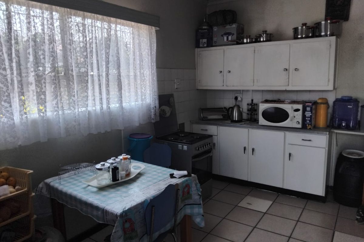 A functional kitchen featuring white built-in cabinetry, tiled flooring, and a freestanding stove, offering potential for modernization and aesthetic updates.