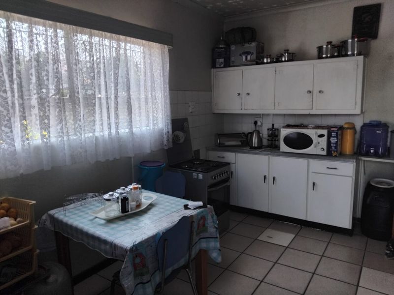 A functional kitchen featuring white built-in cabinetry, tiled flooring, and a freestanding stove, offering potential for modernization and aesthetic updates.