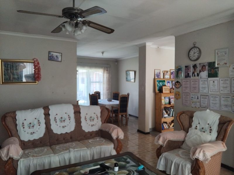 Open plan living and dining area featuring tiled flooring, coved cornicing, and a central ceiling fan.