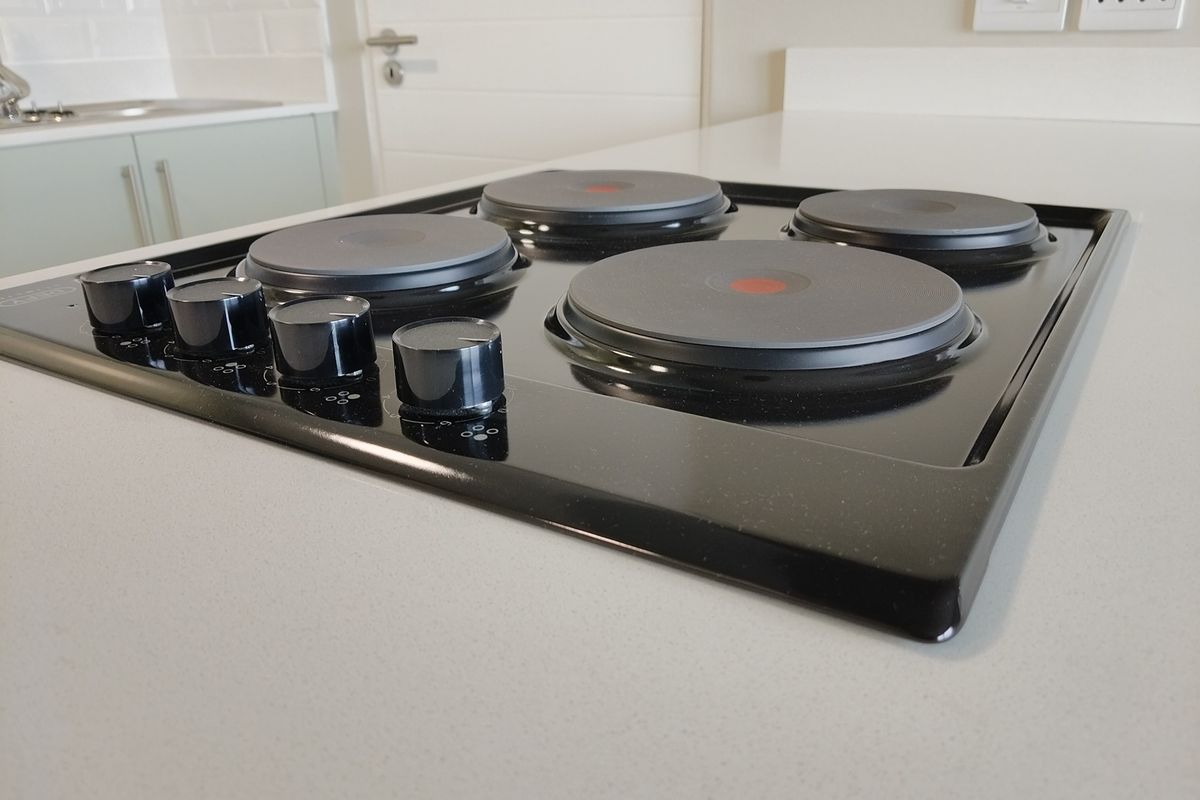 A close-up view of a modern black electric hob set into a clean stone countertop within a contemporary kitchen space.