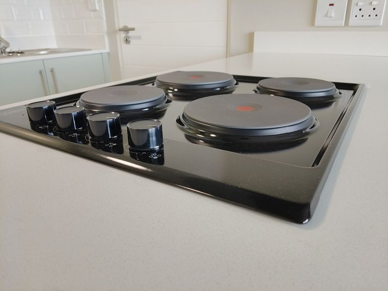 A close-up view of a modern black electric hob set into a clean stone countertop within a contemporary kitchen space.