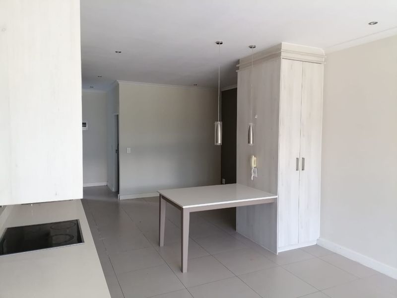 Open-plan living area featuring tiled flooring, recessed lighting, and a built-in kitchen unit with an integrated breakfast counter and electric hob.