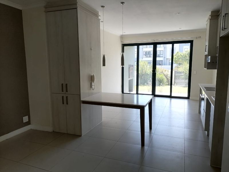 An open-plan living and kitchen area featuring neutral tiled flooring, built-in cabinetry, and large sliding glass doors leading to an outdoor space.