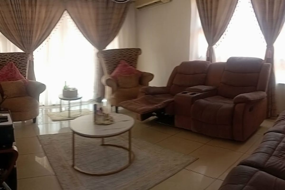 A comfortable living room featuring tiled flooring, a wall-mounted air conditioning unit, and large sliding glass doors that provide natural light.